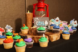A collection of cupcakes with decorations on them and around them at a Wonders of Wildlife birthday party.